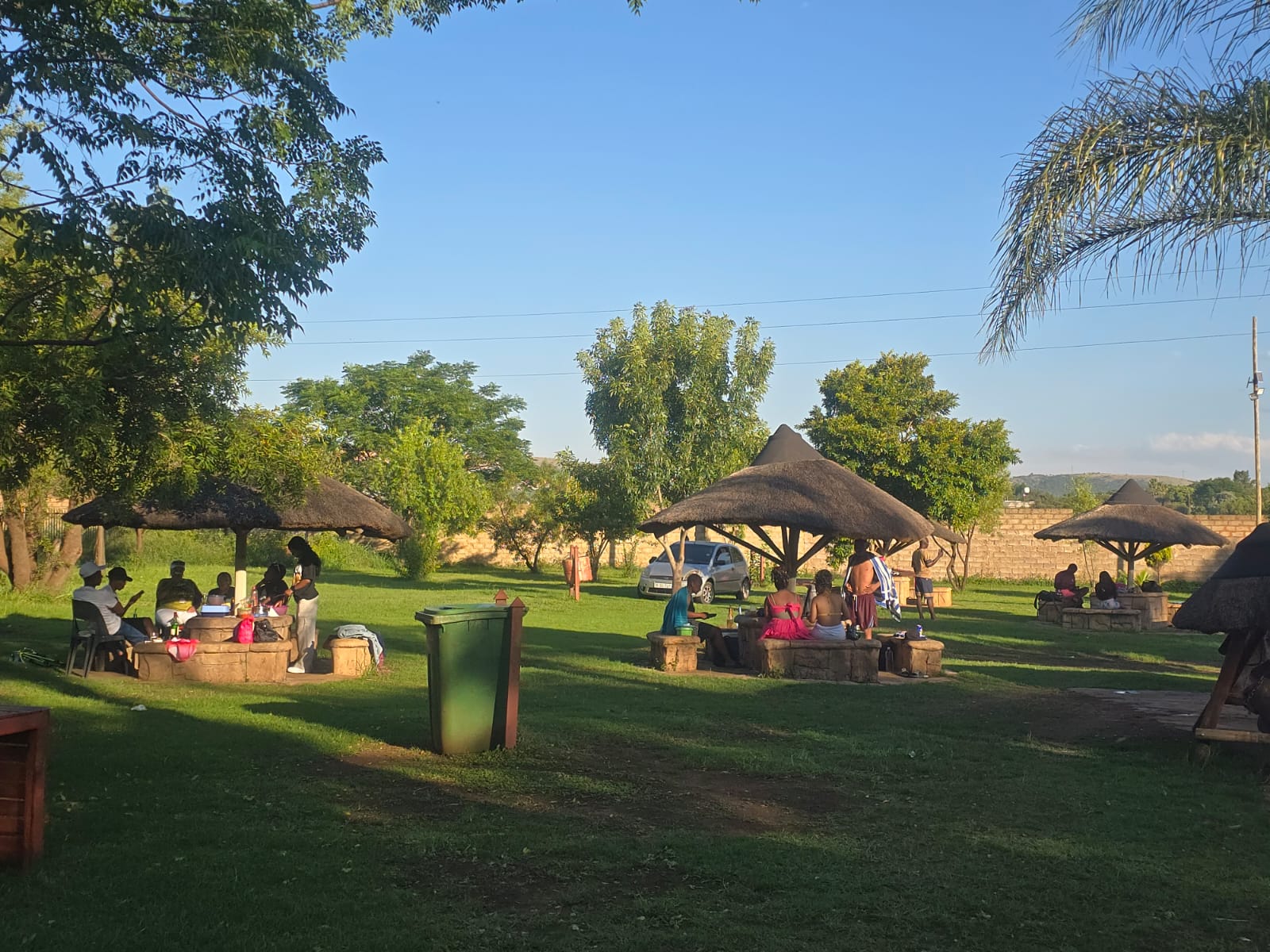 Guests relaxing at thatched picnic gazebos on the lawn