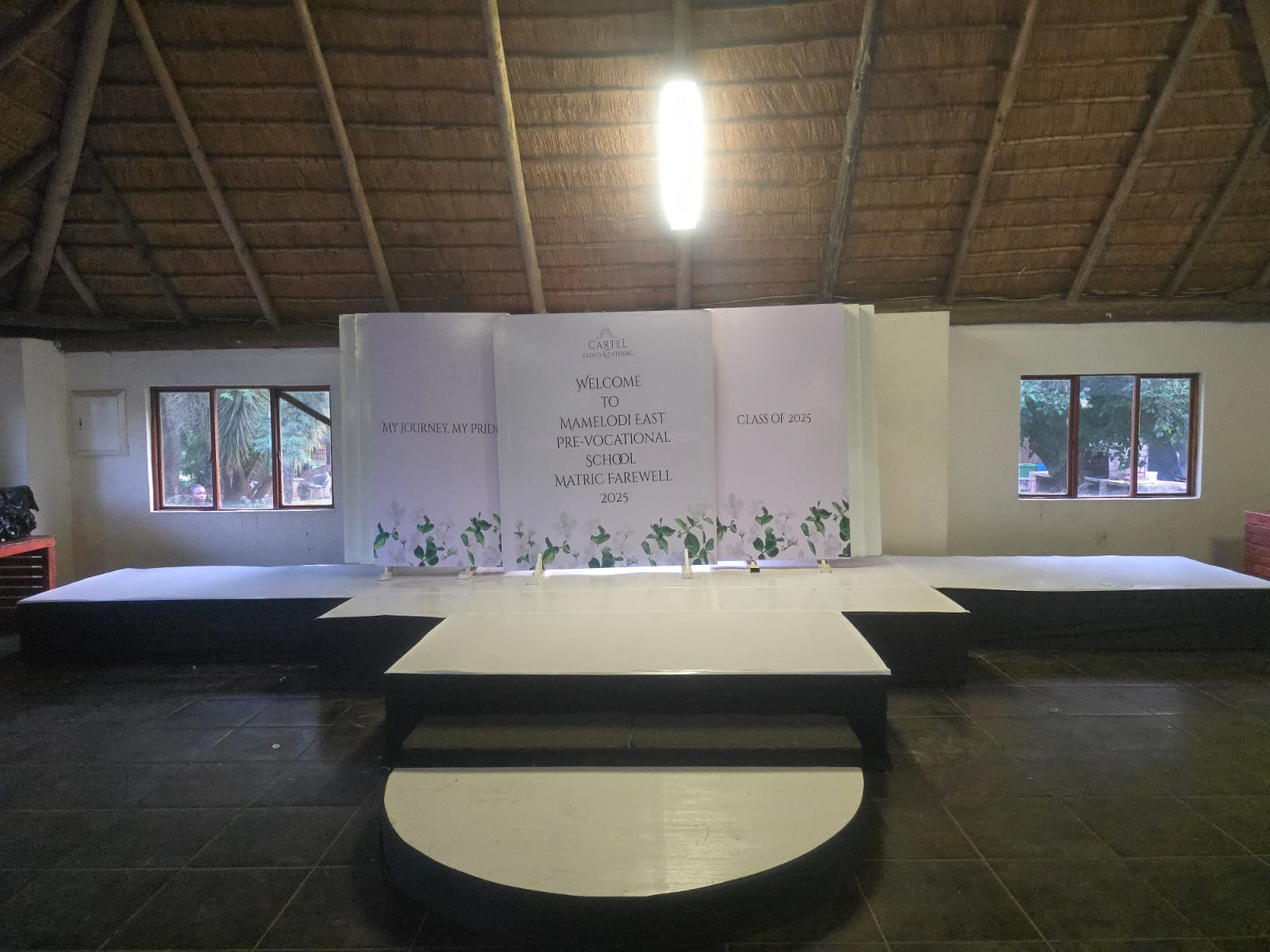 Function hall arranged with a raised stage and printed backdrop