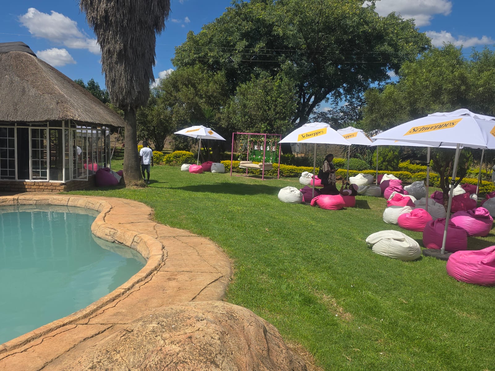 Beanbags and umbrellas set out on the lawn beside the pool